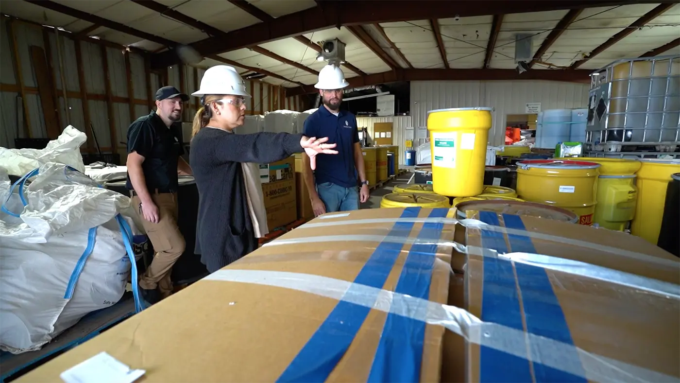 Greer technical staff reviewing packaged waste containers in the Mobile warehouse.
